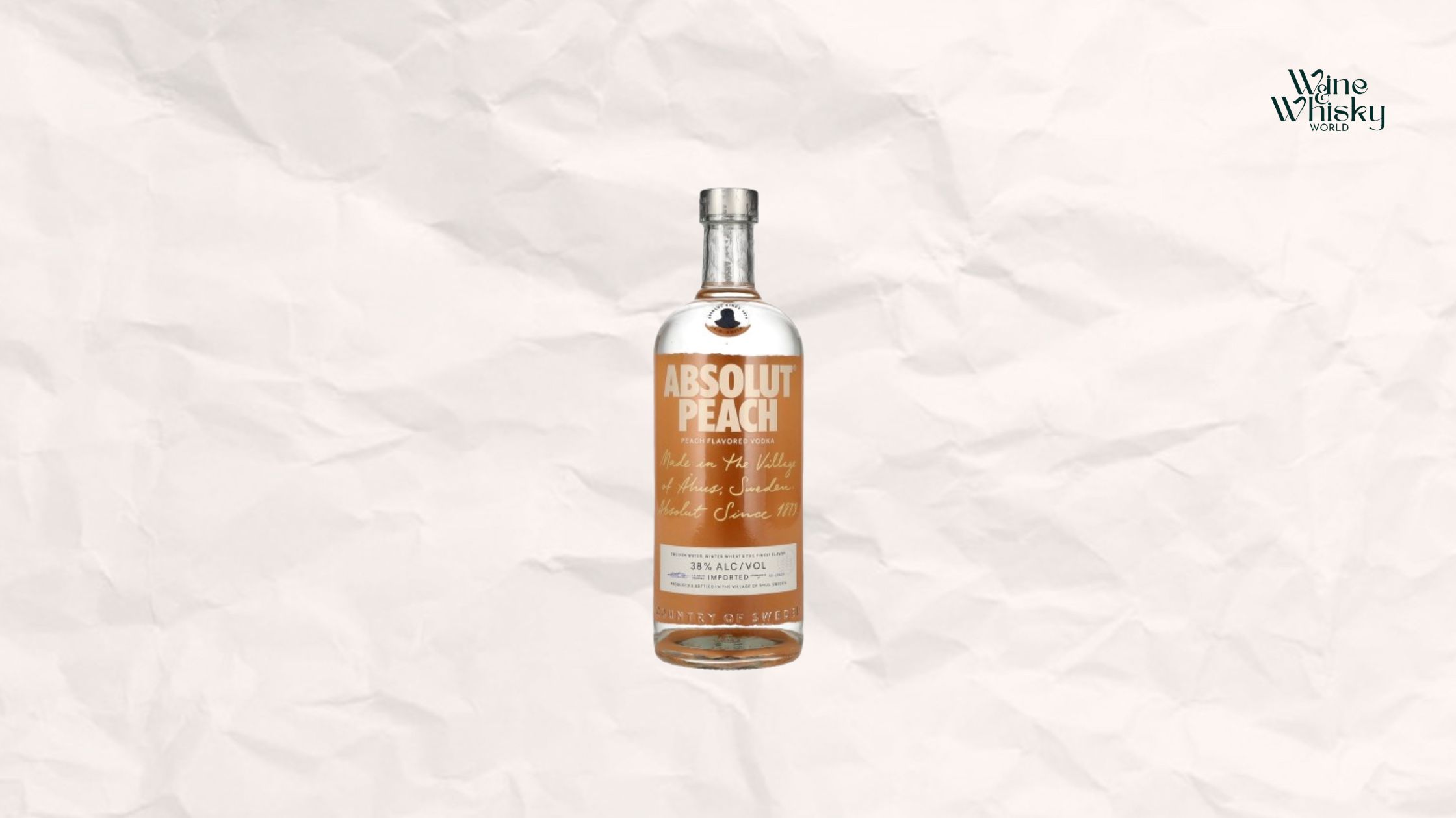 Clear glass bottle of Absolut Vodka with brown and black text on the label, reading 'Absolut Vodka', displayed against a crumpled white paper background with the Wine Whisky World logo in the top right corner.